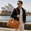 Man holding a Leather Duffle Bag Small by the waterfront, showcasing Italian leather craftsmanship.