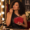 Woman applying lipstick while holding a Croc Embossed Leather Cosmetic Case at a vanity.