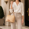 Woman holding a Designer Bucket Bag with chain strap, dressed in a stylish outfit in an elegant setting.