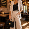 Woman in a stylish beige suit holding the Designer Handbag in a chic café setting.