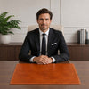 Sophisticated man in a suit sitting at a desk with the Leather Desk Pad, showcasing a stylish and functional workspace.