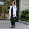 Woman in a white coat holding an Elite Doctors Bag outside a building in Brisbane.