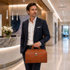 Stylish man in a suit holding the Leather Doctors Bag in a modern office lobby.