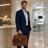 Elegant man in a suit holding the Leather Dr Bag, showcasing the accessory's stylish design and functionality.