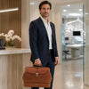 Man in a suit holding the Leather Dr Bag in a modern office setting.