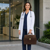 Professional wearing a lab coat holding a Elite Doctors Bag at a medical facility entrance.