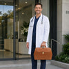 Man in white coat holding Elite Doctors Bag outside a modern building, showcasing elegance and functionality.