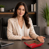 Woman presenting a red Desk Tray on a modern office desk with plants in the background.