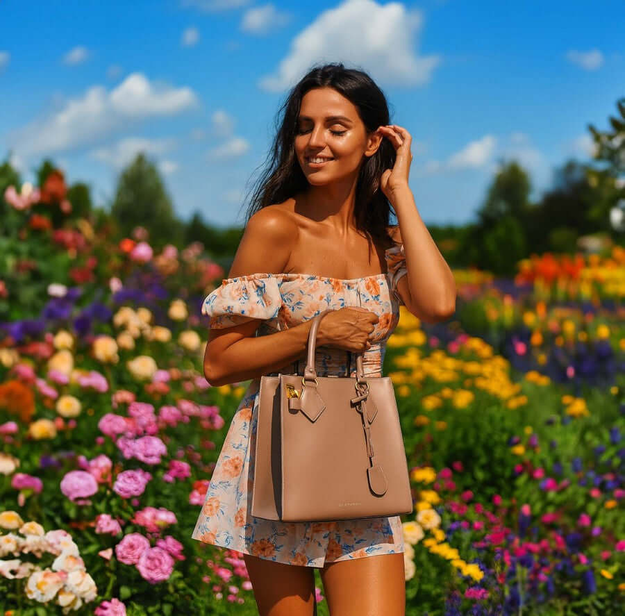 Woman modelling a light taupe Fortuna vertical leather handbag from the Outlet range