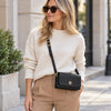 A woman wearing a white sweater showcasing the black Genuine Leather Shoulder Bag in a street setting.