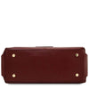 An underneath view of the Bordeaux pebbled Italian leather duffle bag shown from the bottom front view, featuring four gold-tone metal studs on the corners