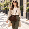Woman Walking In The Street Wearing The Chocolate Italian Suede Drawstring Shoulder Bag As A Crossbody Bag