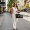Stylish woman in white outfit walking on city street with the Italian Handbag, showcasing elegance and sophistication.