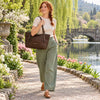 Woman walking by a lake carrying a Italian Leather Tote Bag, showcasing elegance and practicality.