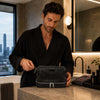 Man in bathrobe using Mens Toiletry Bag Leather in a modern bathroom setting.