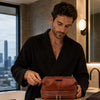 Man in a bathrobe using the Mens Toiletry Bag Leather in a modern bathroom setting.