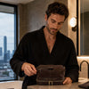 Man in a robe using the Mens Toiletry Bag Leather in a modern bathroom setting.