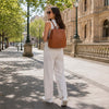 Stylish woman wearing a the Ladies Backpack, walking in a sunlit city street, showcasing genuine Italian leather design.