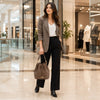 A woman stands in a modern shopping mall corridor  while carrying a dark taupe ladies bucket bag