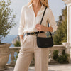Stylish woman wearing a shirt and trousers holding a Leather Clutch Bag for Women in an outdoor setting.