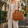 Ladies Leather Handbag being carried by a woman in a stylish outfit on a sunny street.