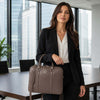 A professional woman in a suit holding a Ladies Leather Laptop Case in an office setting.