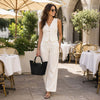 A stylish woman wearing a light outfit, holding a Ladies Leather Tote Handbag at a café.