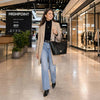A woman in a stylish outfit with a Large Italian Handbag, walking through a modern shopping mall.