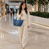 A woman walking in a mall with a Large Italian Handbag, pebbled leather, stylishly paired with light attire.