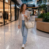 Young woman in casual attire carrying a Large Italian Handbag while walking in a shopping mall.