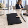  The Black Leather Planner - Weekly Diary sitting on a corporate desk with a business woman in the background 