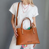 Crossbody View Of A Woman Holding The Natural Leather Tote Bag