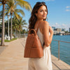 Woman wearing a Leather Backpack For Women while walking by the water on a sunny day.