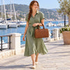 Woman in a green dress walking by the water with a Italian Leather Bowler Bag.