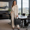 Elegant woman in a suit holding a Leather Briefcase For Women in a modern office setting.