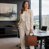 Woman in a suit holding a Leather Briefcase For Women in a modern office setting.