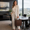 Woman in a beige suit holding a Leather Briefcase For Women in a modern office setting.