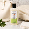 Leather Colourless Leather Cleaner bottle next to a cream leather bag and a cleaning cloth.