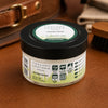 Leather Conditioner Cream jar on a leather surface, showcasing its protective properties for leather care.