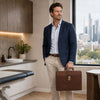Man in a blue blazer holding a Leather Doctor Bag in an office setting with city skyline.