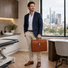 Man in a suit holding a Leather Doctor Bag in modern office setting with city view.