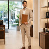 A professional man in a beige suit holding the Leather Document Case With Handle inside a store.