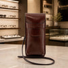 Leather Eyeglasses Case displayed on a marble counter, showcasing rich dark brown full grain leather and a detachable shoulder strap.