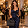 A woman in a navy dress holding a Leather Handbag and Wallet Set at an elegant event.