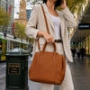 Person carrying a Italian Leather Handbag while wearing a stylish outfit in an urban setting.