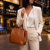 A woman in a stylish outfit holding a Italian Leather Handbag in front of Crown Melbourne.
