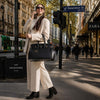 Leather Womens Handbag displayed by a woman in a city street, dressed in stylish attire, enjoying a sunny day.