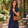 Woman wearing a TL BAG Leather Ladies Handbag, showcasing its stylish design in a floral outdoor setting.
