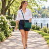 Woman in the park with the green Leather Ladies Handbag in pebbled leather with a leather green shoulder strap 