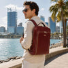 Man wearing a stylish Bangkok Leather Laptop Backpack near waterfront with city skyline.
